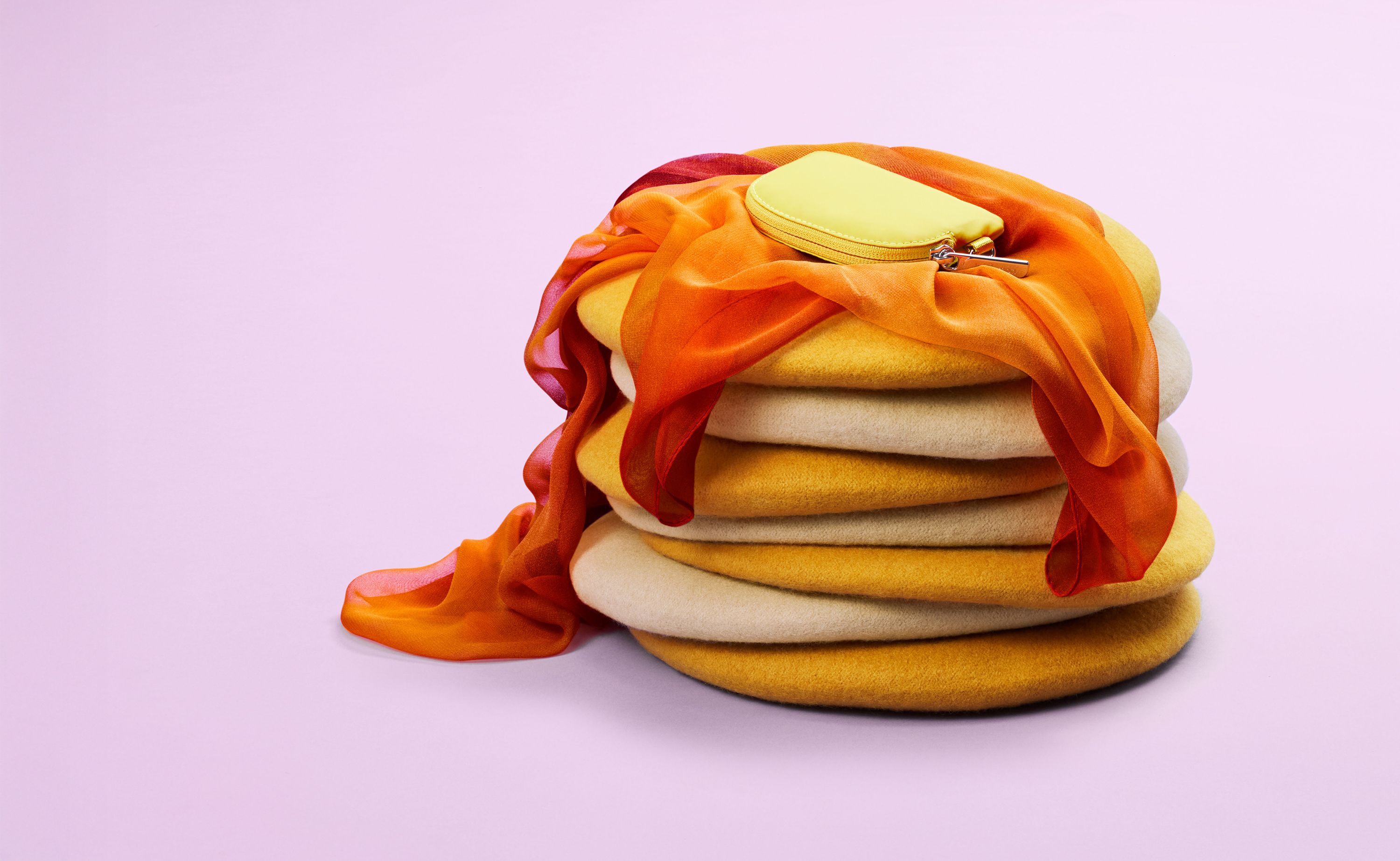 Folded fabric discs stacked to resemble pancakes, with an orange silk ribbon as syrup and a yellow pouch as butter.